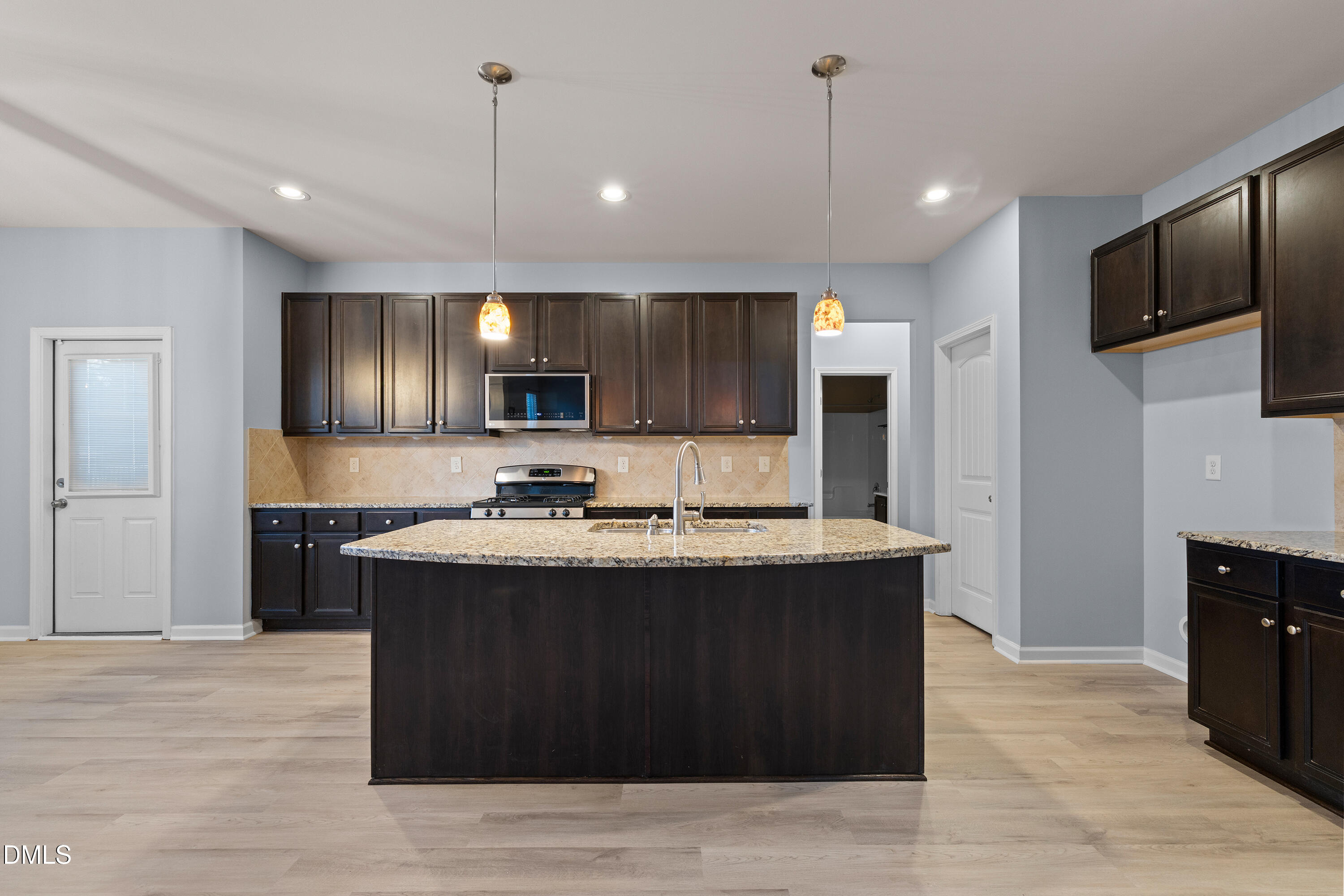 396 Naples Lane Clayton, NC 27527 - Photo 10 of 33 a kitchen with kitchen island a sink and a stove top oven with wooden floor