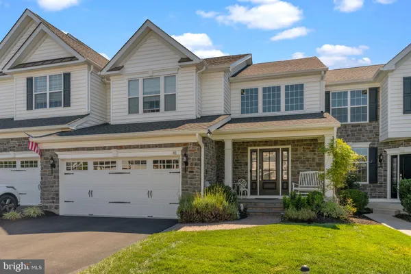 a view of a house with small yard plants and large tree