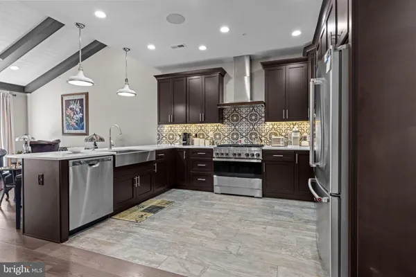 a kitchen with stainless steel appliances kitchen island granite countertop a refrigerator and a sink