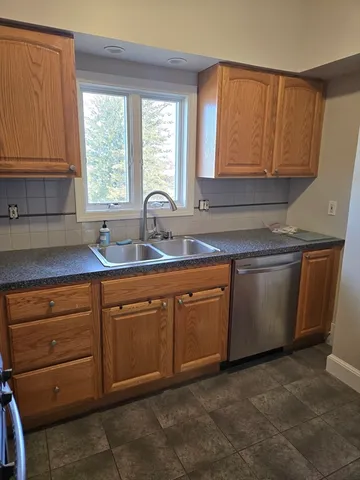 a kitchen with stainless steel appliances granite countertop a sink window and cabinets