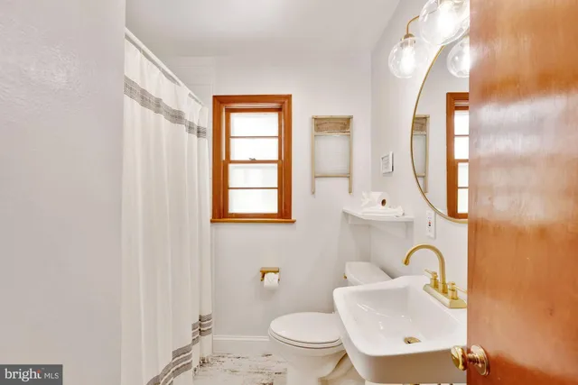 a bathroom with a granite countertop sink mirror vanity and toilet