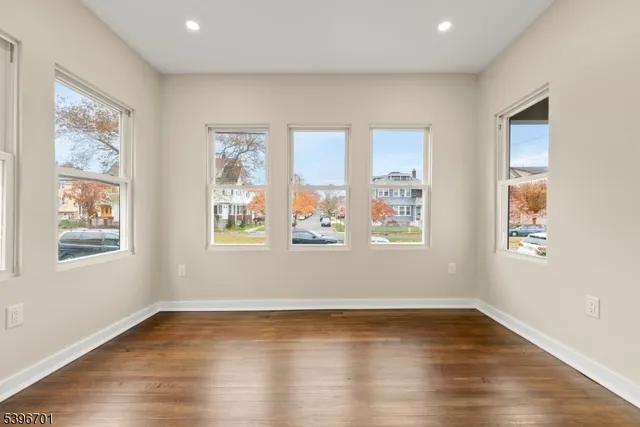 a view of an empty room with wooden floor and window