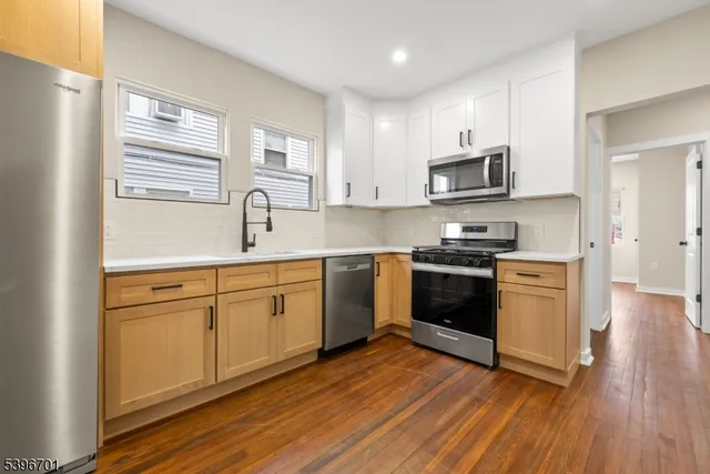 a kitchen with granite countertop cabinets stainless steel appliances and wooden floor