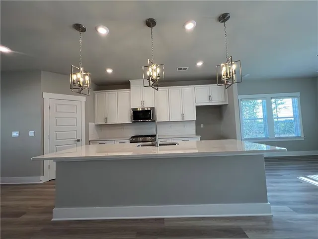 a large kitchen with granite countertop a large kitchen island a sink dishwasher a refrigerator and a fireplace