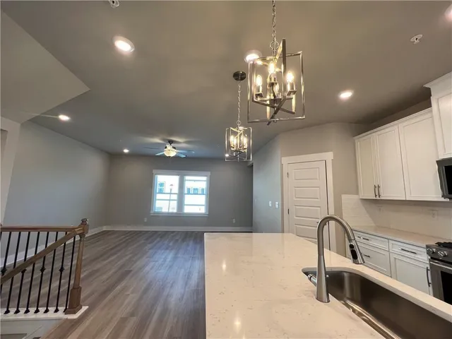 a kitchen with stainless steel appliances granite countertop a sink dishwasher a stove and a dining table with wooden floor