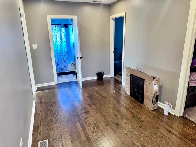 a view of an empty room with wooden floor and a fireplace