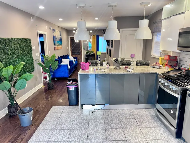 a kitchen with stainless steel appliances granite countertop a refrigerator a stove a sink dishwasher and a dining table with wooden floor