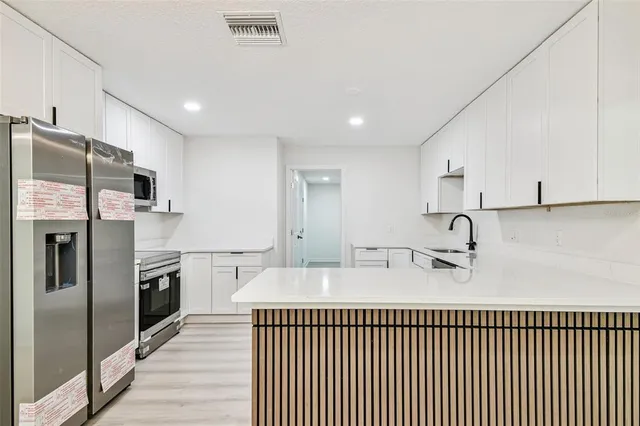 a kitchen with white cabinets and stainless steel appliances