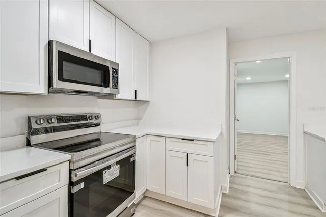 a kitchen with white cabinets white appliances and sink