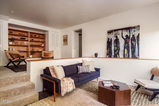 a living room with furniture a rug and a shelf