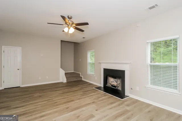 a view of an empty room with wooden floor fireplace and a window