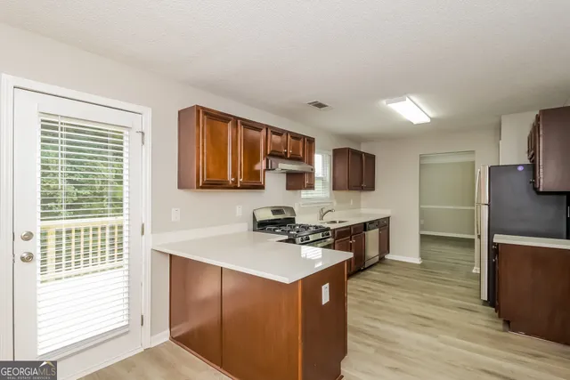 a kitchen with stainless steel appliances granite countertop a stove top oven a sink dishwasher a refrigerator and a microwave oven with wooden floor