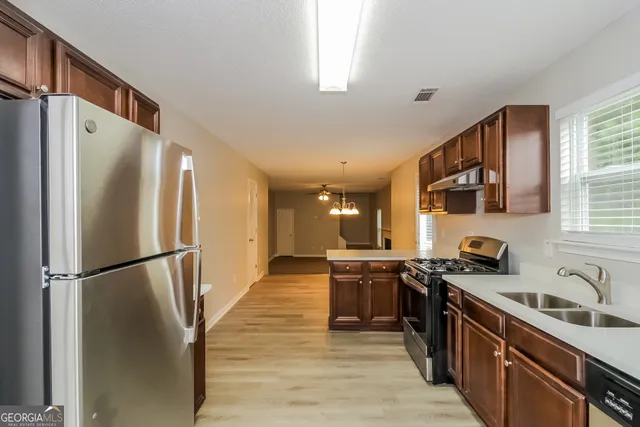 a kitchen with stainless steel appliances granite countertop a refrigerator a sink dishwasher a stove and a refrigerator