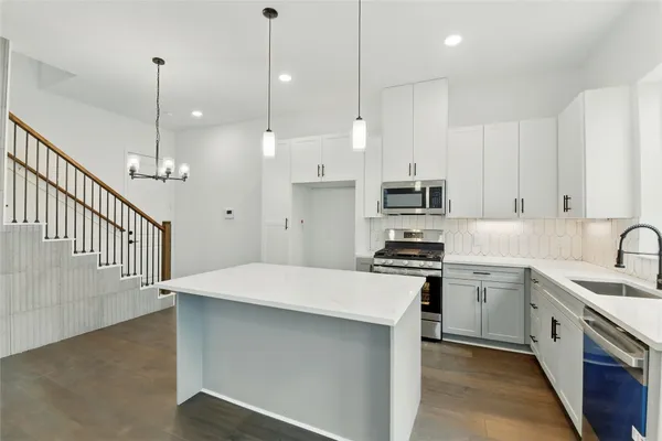 a kitchen with kitchen island a sink stainless steel appliances and white cabinets