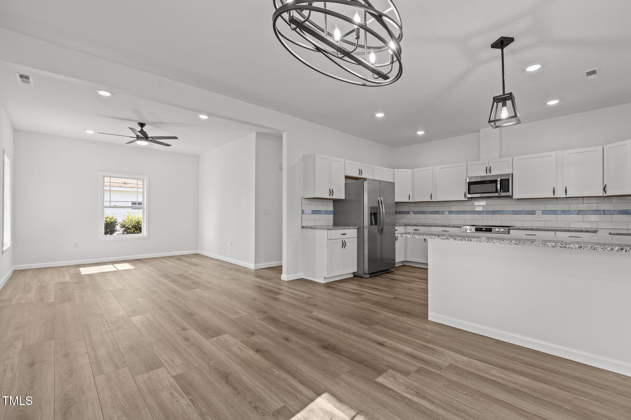 112 Edgewood Drive Roxboro, NC 27573 - Photo 12 of 37 a view of kitchen with stainless steel appliances granite countertop a stove top oven a refrigerator cabinets and wooden floor