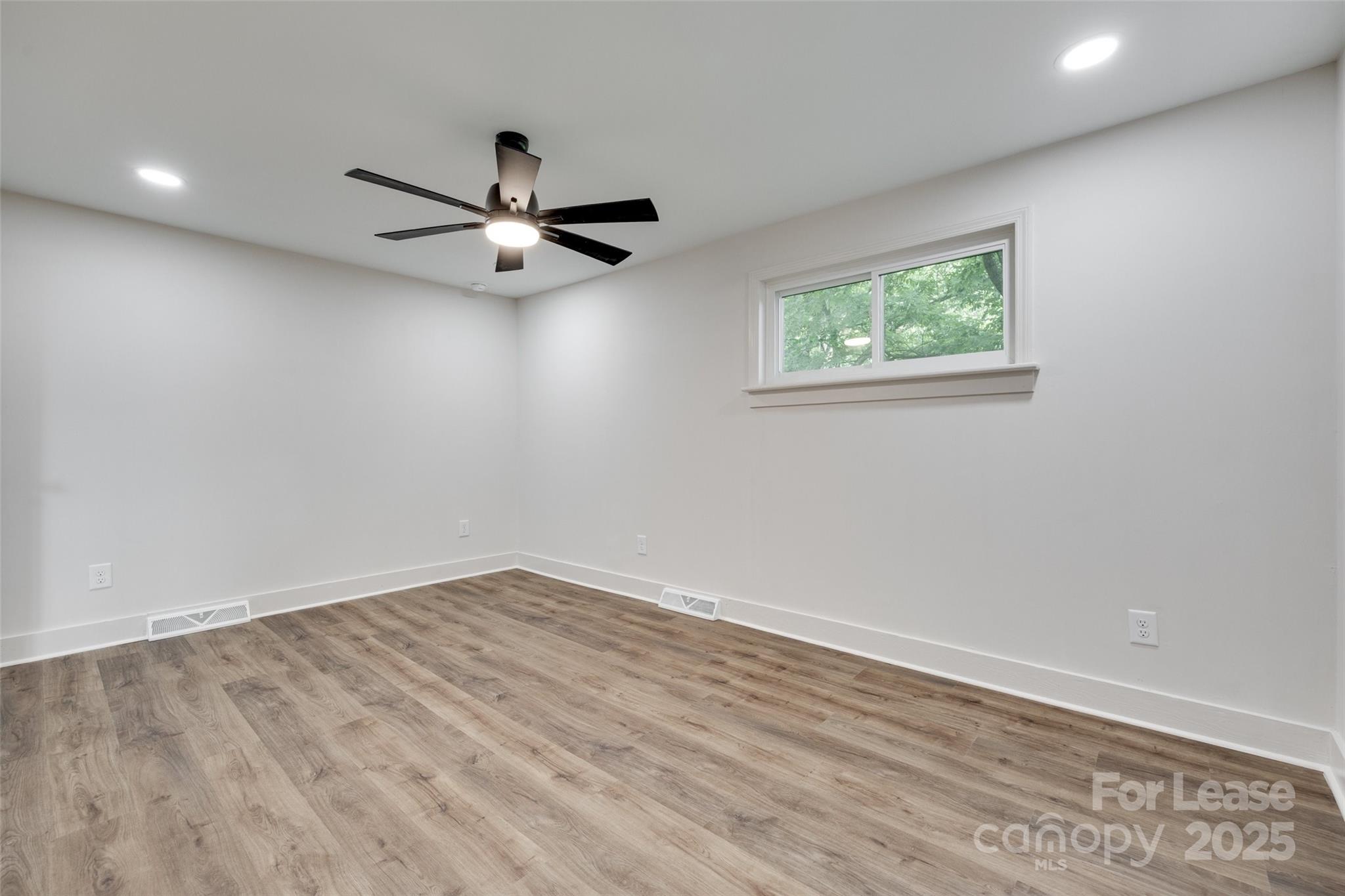 3113 E Highway, Unit 218 Monroe, NC 28110 - Photo 15 of 27 an empty room with wooden floor ceiling fan and windows