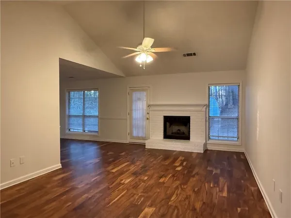 a view of an empty room with wooden floor fireplace and a window