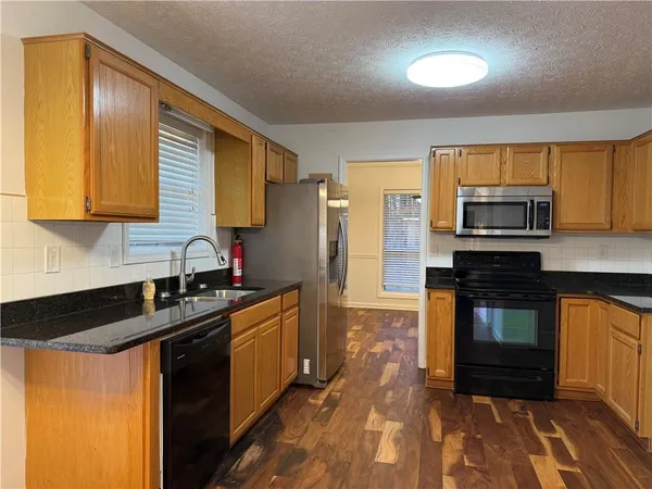 a kitchen with granite countertop a stove a sink and a microwave