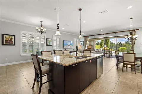 a dining hall with stainless steel appliances granite countertop furniture a large window and a chandelier