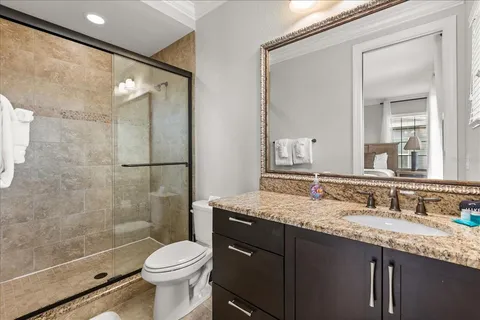 a bathroom with a granite countertop toilet sink shower and mirror