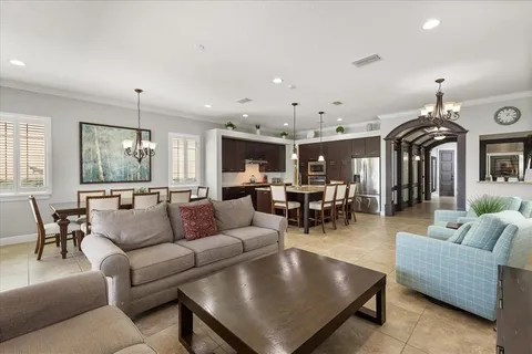 a living room with furniture kitchen view and a chandelier