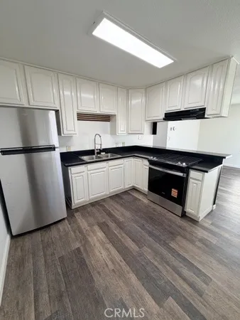 a kitchen with granite countertop a refrigerator and a stove top oven