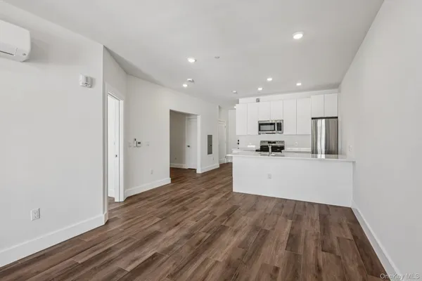 a view of a kitchen with cabinets stainless steel appliances wooden floor and a window