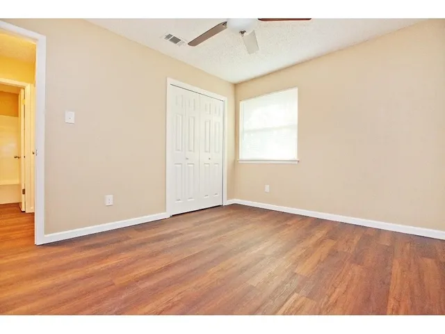 an empty room with wooden floor and windows