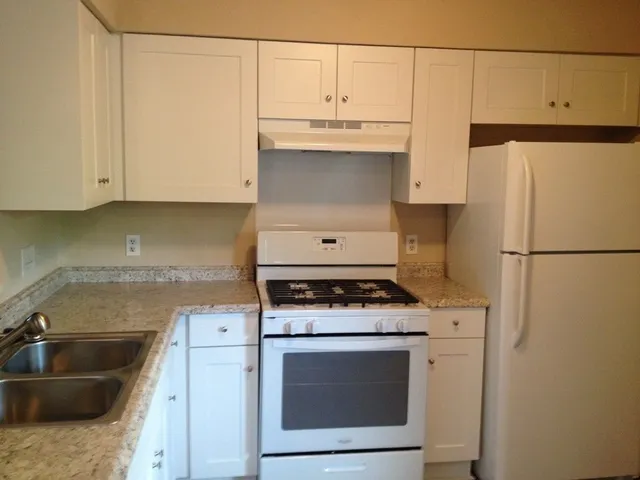 a kitchen with granite countertop a sink stove and refrigerator