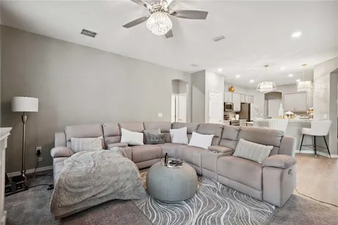 a living room with furniture kitchen view and a chandelier