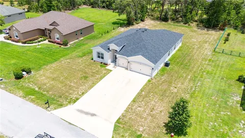 a view of a house with a big yard and large trees
