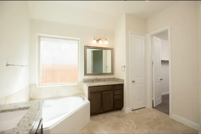 a spacious bathroom with a tub sink and mirror