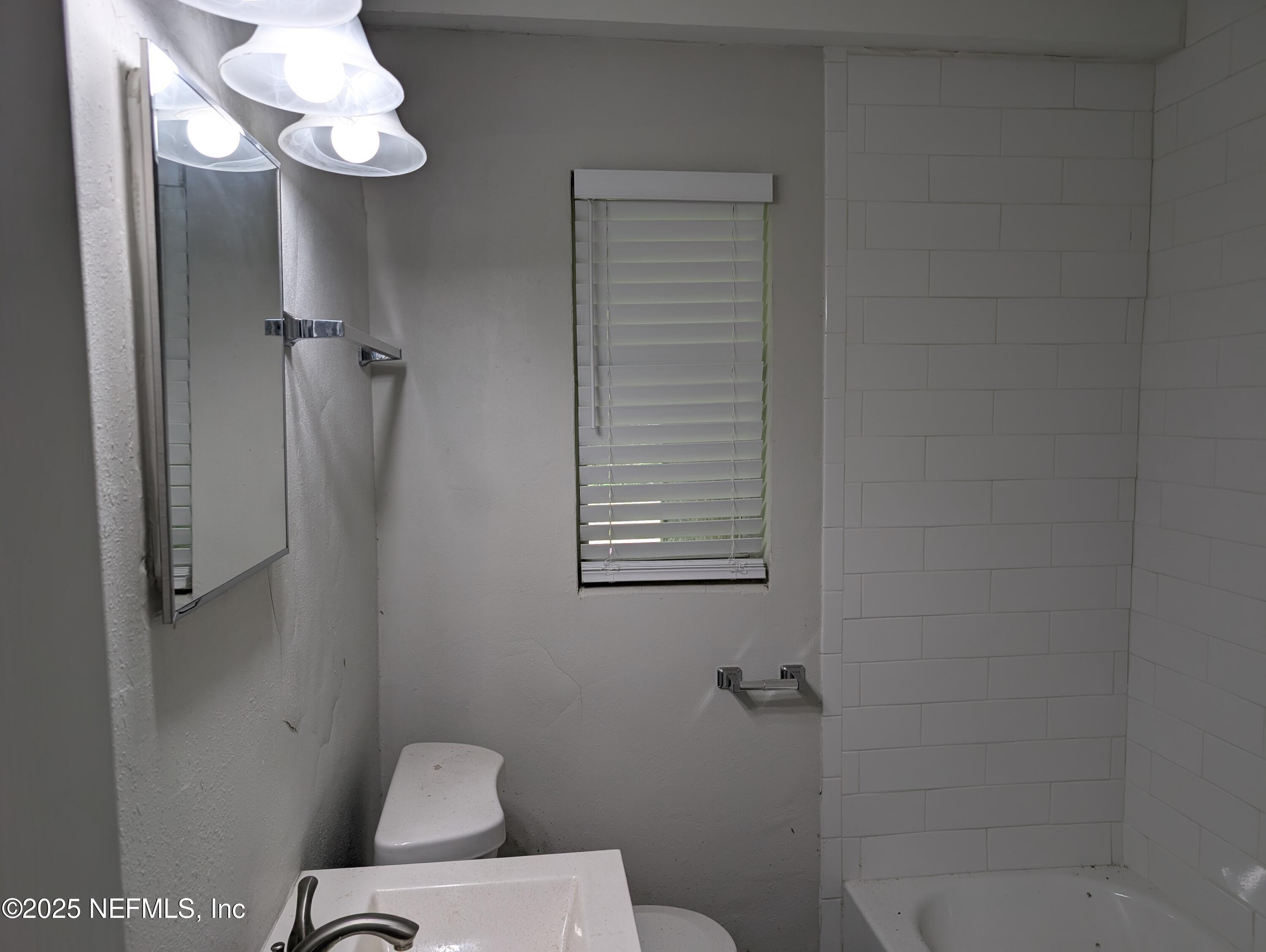 1339 Ellis Road South Jacksonville, FL 32205 - Photo 16 of 26 a bathroom with a toilet a sink and mirror