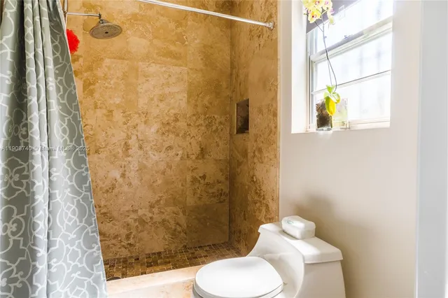 a bathroom with a toilet and a shower curtain