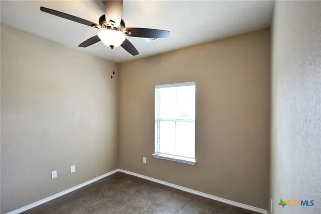 an empty room with a window and a fan