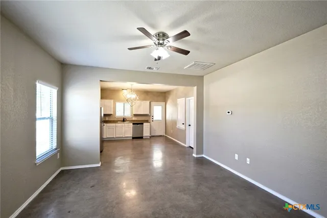 a view of empty room with window and ceiling fan