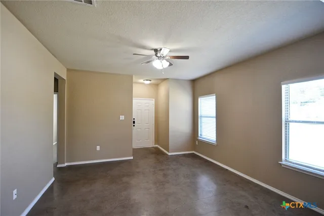 an empty room with windows and ceiling fan