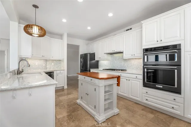 a kitchen with stainless steel appliances granite countertop a sink stove a refrigerator and white cabinets with wooden floor