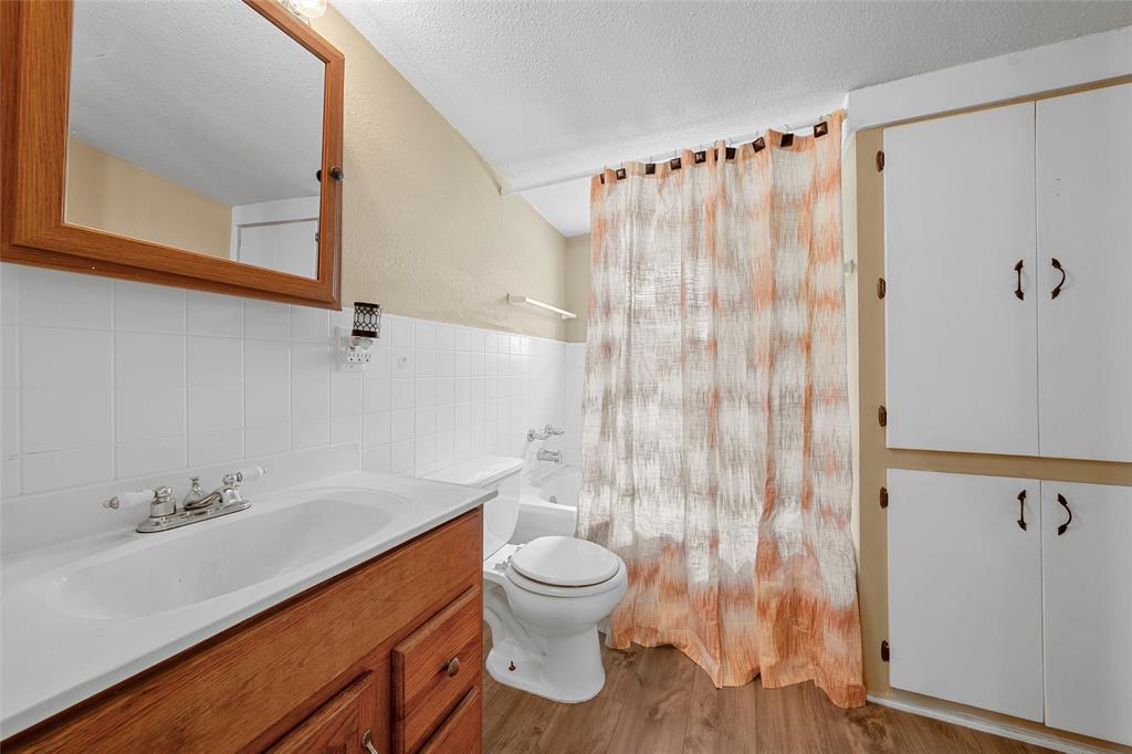 4704 Williams Road Bellmead, TX 76705 - Photo 17 of 32 Bathroom featuring a wood-finish vanity with an integrated sink, white subway tile backsplash, and a framed medicine cabinet