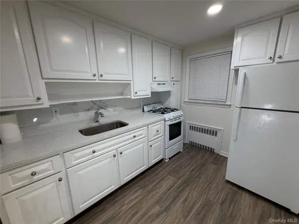a kitchen with granite countertop white cabinets and white appliances