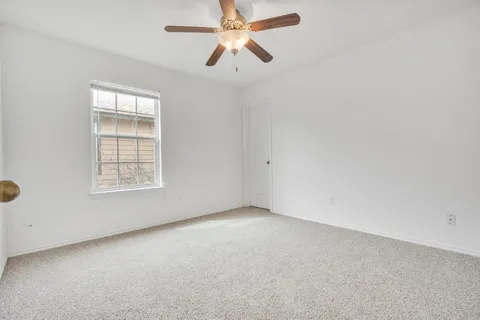 an empty room with chandelier fan and windows