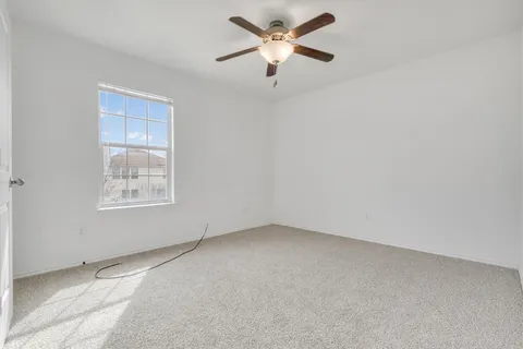 an empty room with a window and a fan