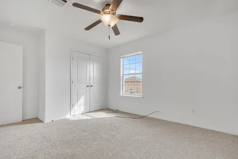 an empty room with a window and a fan