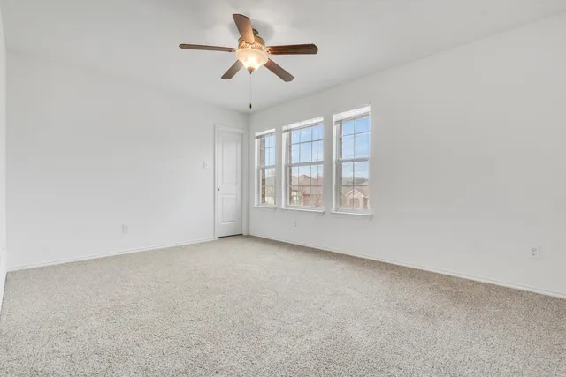 an empty room with windows and ceiling fan