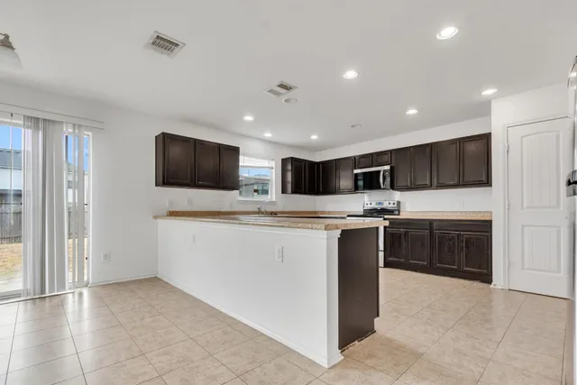 a kitchen with granite countertop wooden cabinets stainless steel appliances and a window