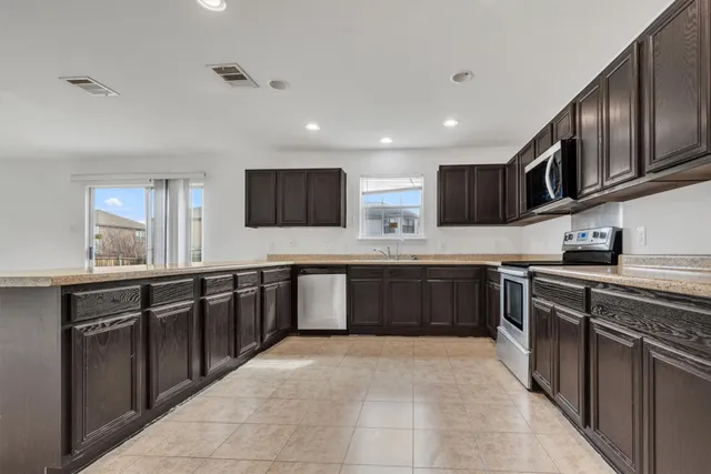 a large kitchen with stainless steel appliances a sink and cabinets