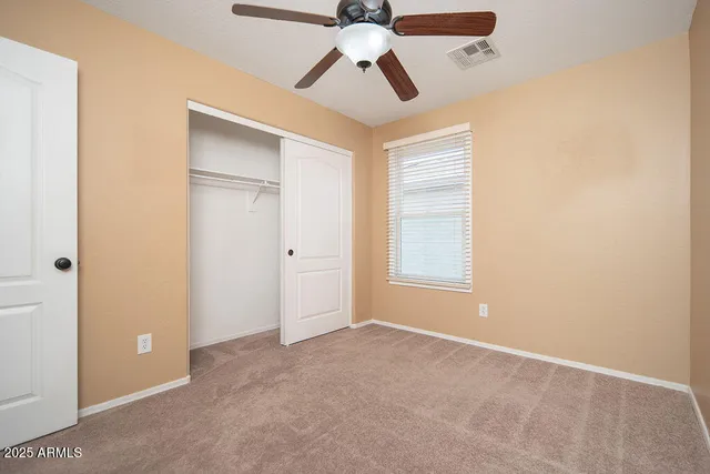 an empty room with chandelier fan and windows