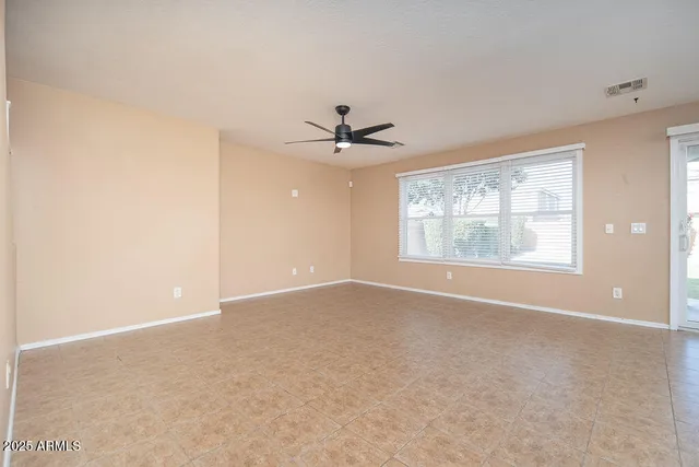 an empty room with windows and ceiling fan