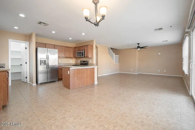 an empty room with stainless steel appliances kitchen island granite countertop a refrigerator and a sink