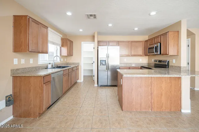 a kitchen with stainless steel appliances granite countertop a stove top oven a sink a refrigerator and white cabinets